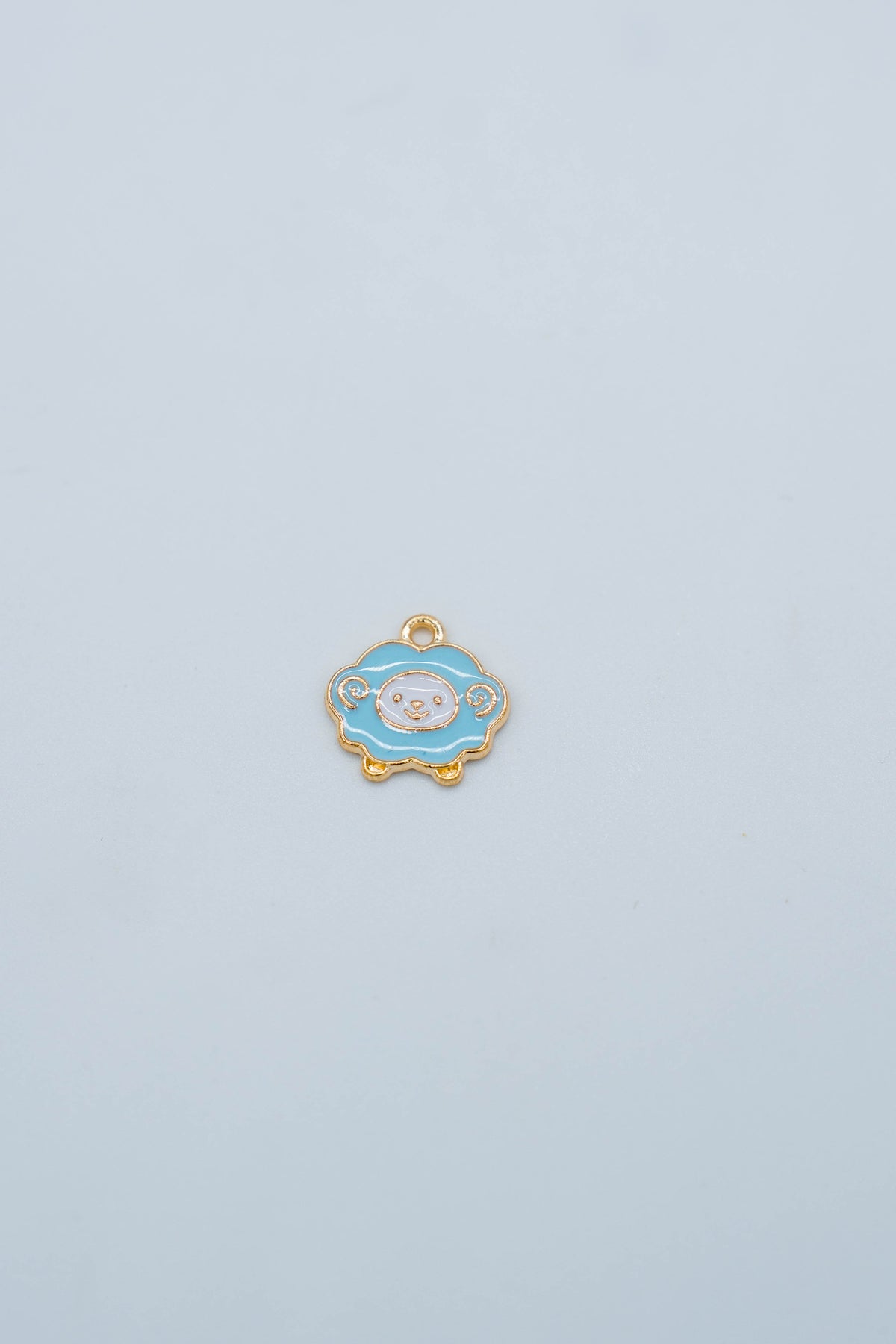 Blue metal sheep charm on gold-toned backing