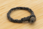 Close up gray wool bracelet made from Delilah the Finnsheep on a wooden background