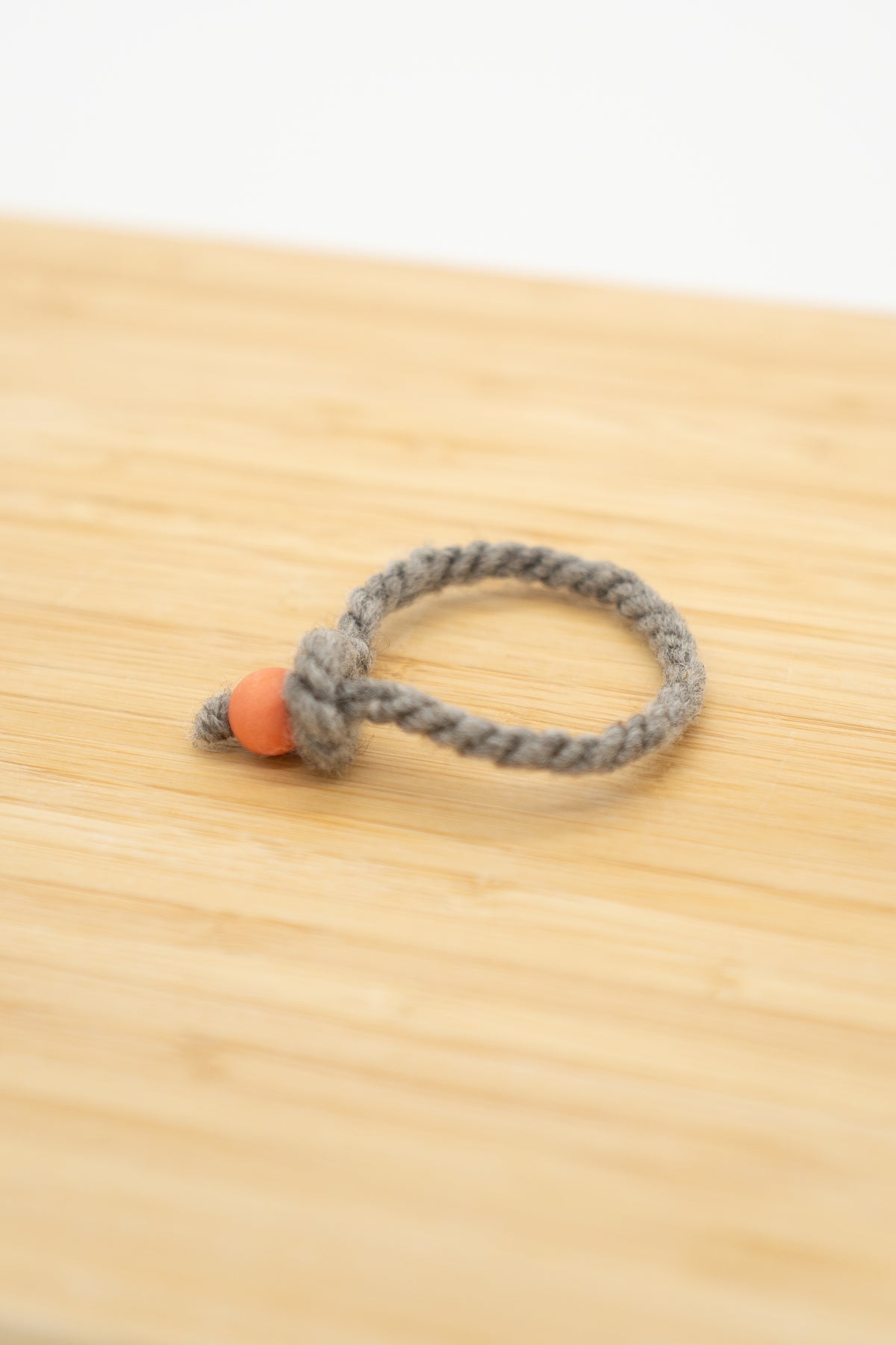 Light gray wool bracelet made from Eddie the Shetland ram on a wooden background