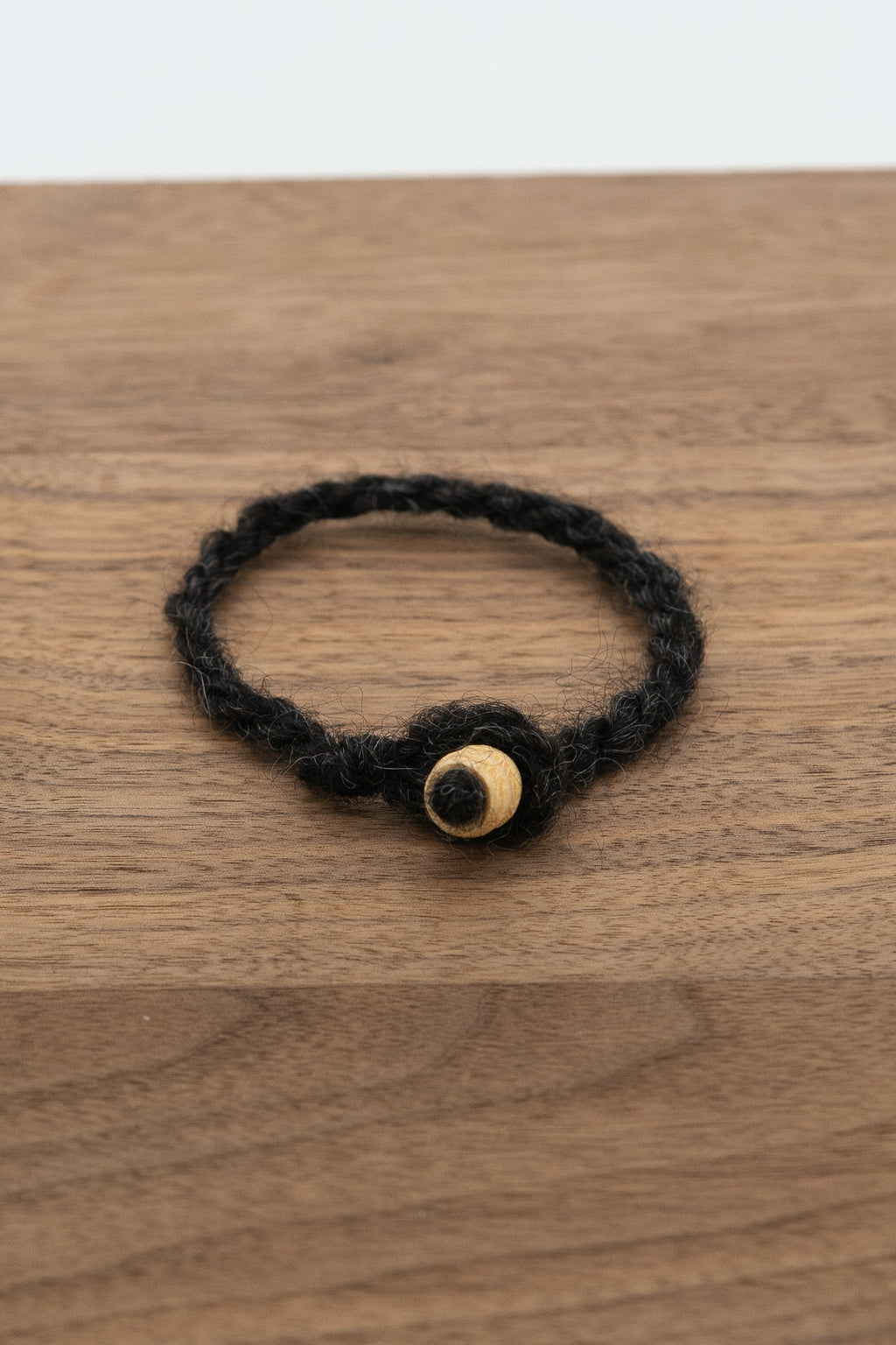 Woolen bracelet with natural bead from Fiona the Finnsheep on a wooden background