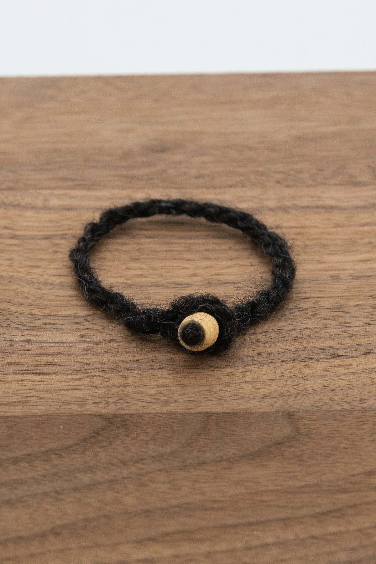 Woolen bracelet with natural bead from Fiona the Finnsheep on a wooden background