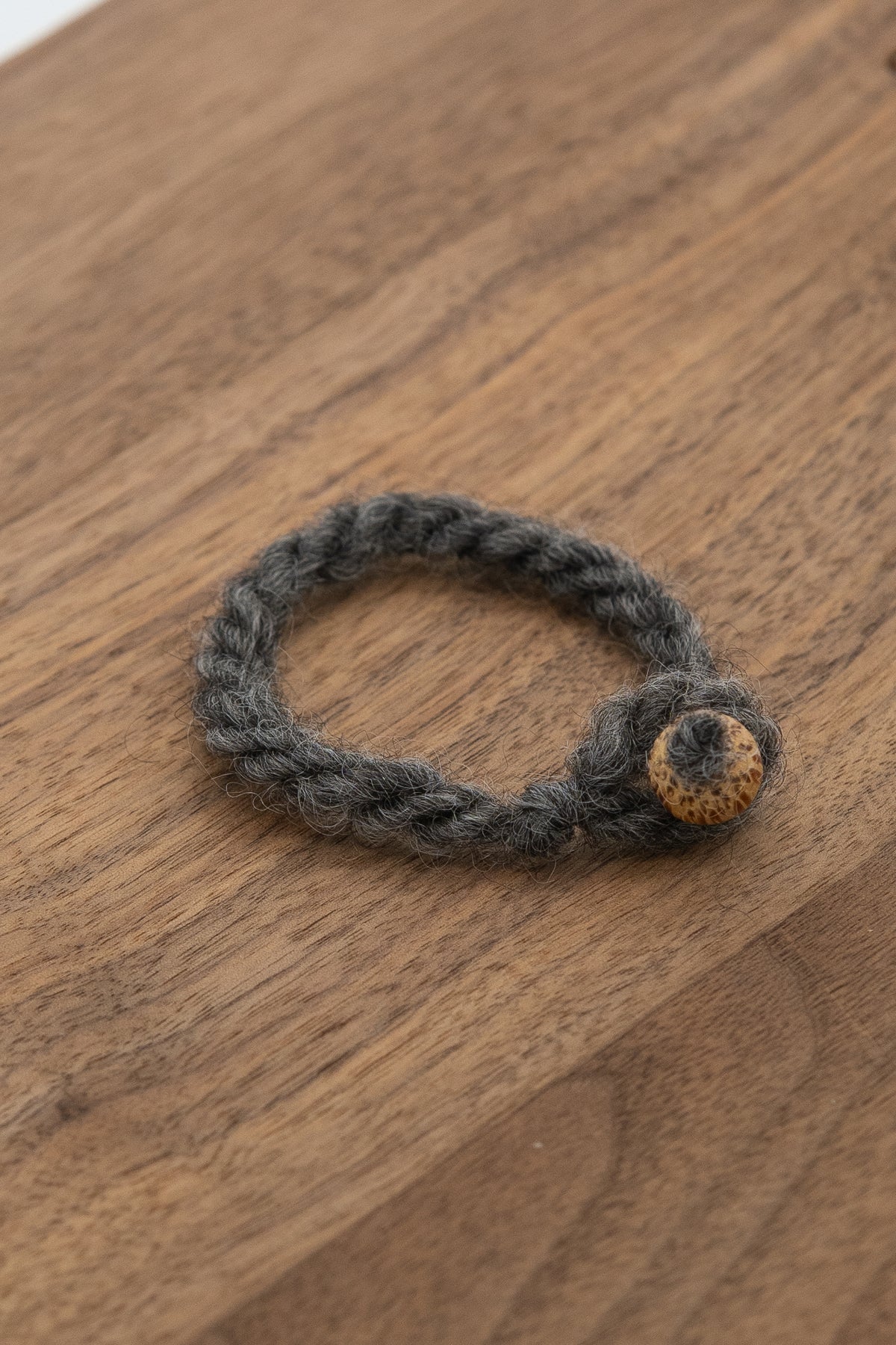 Dark Gray wool bracelet made from Magnolia the sheep on a wooden background