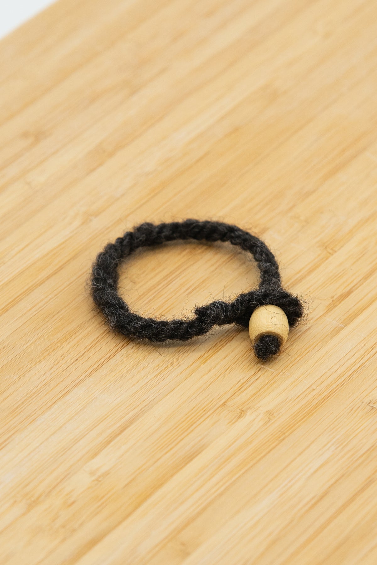 Black wool bracelet handmade from Norma the Shetland sheep on a wooden background