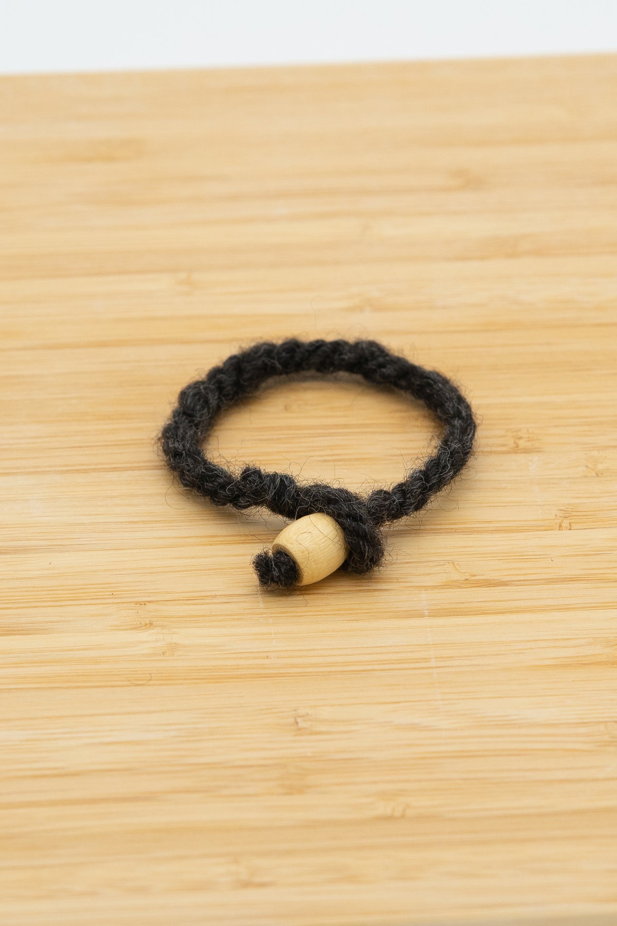 Black antural wool bracelet handmade from Norma the Shetland sheep on a wooden background