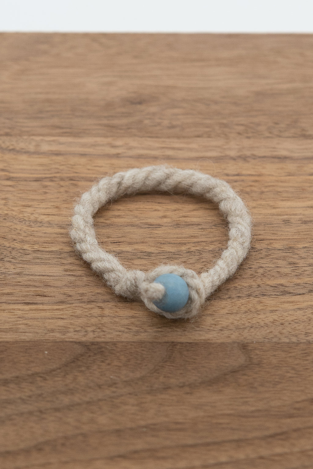 Light gray natural wool bracelet from Padraic the Shetland ram on a dark wooden background