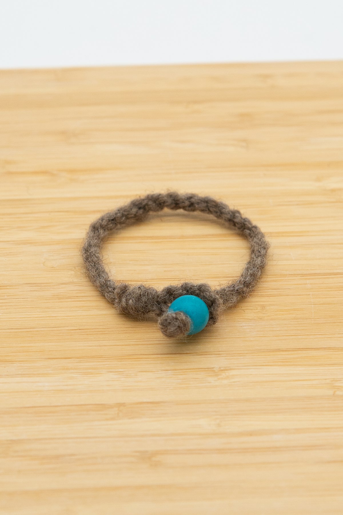 Brown wool bracelet made from Paula the Shetland sheep placed on a wooden background