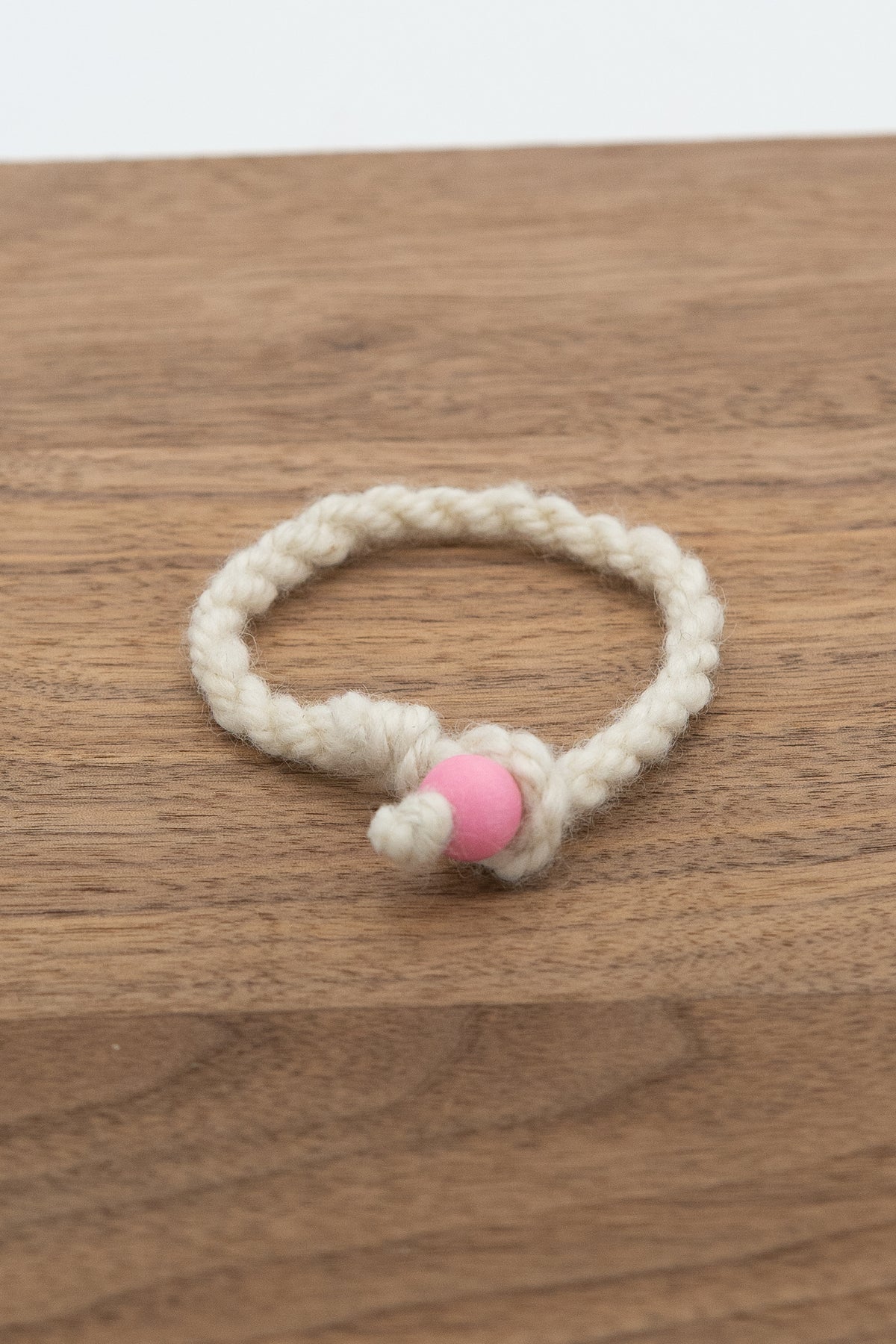 White wool bracelet handmade from Valkia the Finnsheep on a wooden background 